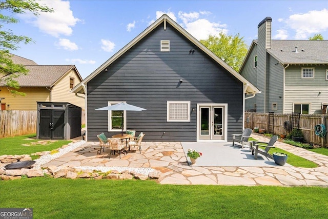 back of house with fence, a storage shed, an outdoor structure, a patio, and a lawn