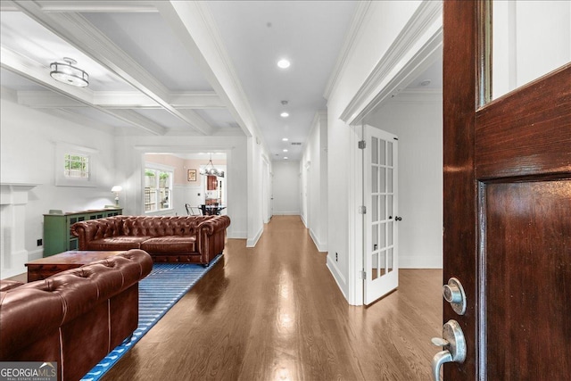 interior space with wood finished floors, ornamental molding, a chandelier, beamed ceiling, and baseboards