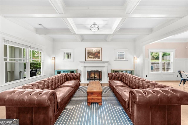 living area with coffered ceiling, ornamental molding, a warm lit fireplace, and beam ceiling