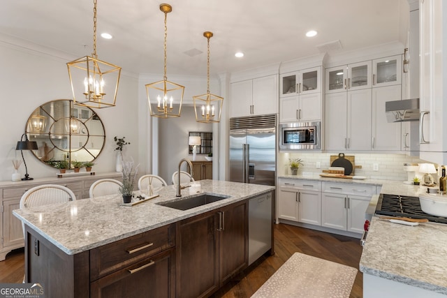 kitchen with a sink, white cabinets, crown molding, built in appliances, and tasteful backsplash