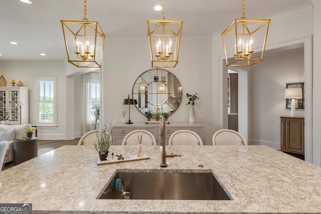 kitchen with open floor plan, an inviting chandelier, crown molding, and a sink