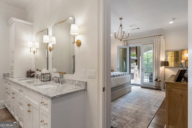 ensuite bathroom with a notable chandelier, ensuite bathroom, crown molding, and a sink