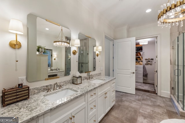 full bath with an inviting chandelier, a stall shower, ornamental molding, and a sink