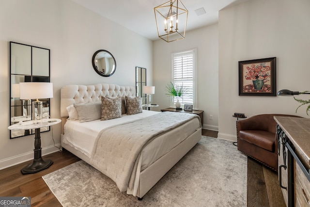 bedroom with a notable chandelier, baseboards, and wood finished floors