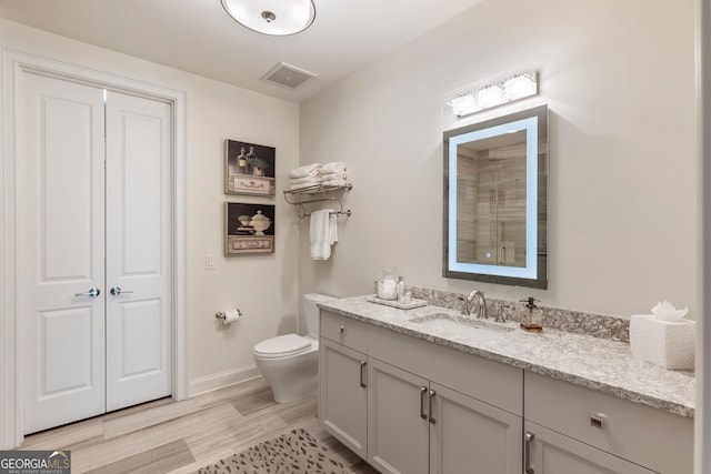 full bathroom with toilet, wood finished floors, vanity, visible vents, and baseboards
