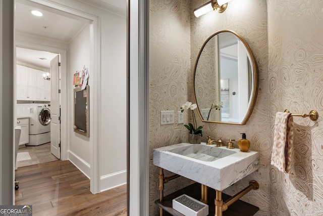 bathroom with ornamental molding, wallpapered walls, wood finished floors, and washer / clothes dryer