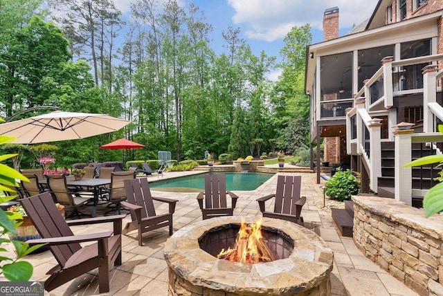 5475 Copper Creek Pass, Cumming, GA 30040 - outdoor pool with an outdoor fire pit, a patio, a sunroom, and view of wooded area