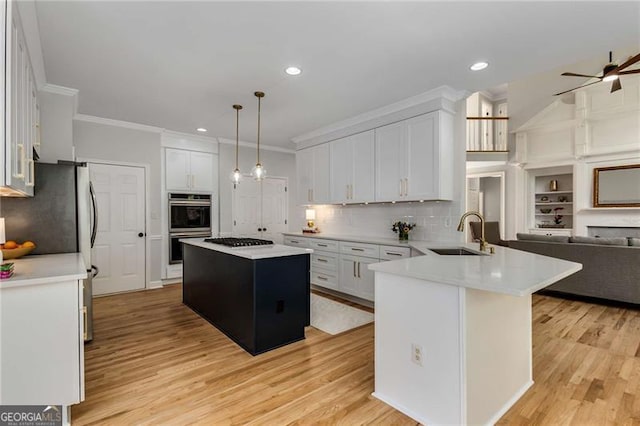 kitchen with crown molding, a sink, a peninsula, open floor plan, and double wall oven