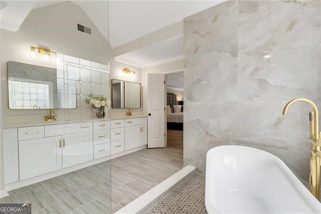 bathroom featuring a sink, double vanity, tile walls, ornamental molding, and a soaking tub