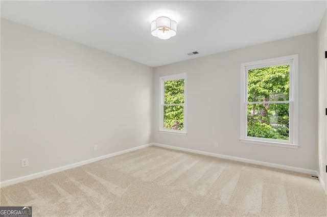empty room featuring baseboards, visible vents, and carpet
