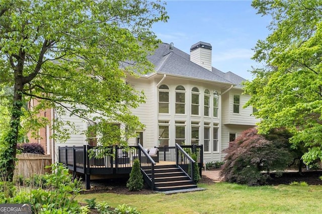 rear view of house featuring a yard, a deck, fence, and a chimney