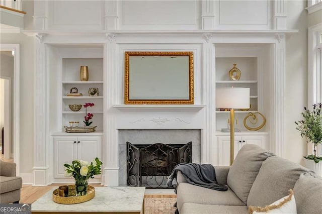 living area featuring a fireplace, built in shelves, and wood finished floors