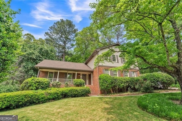 view of front of home with a porch, brick siding, and a front lawn