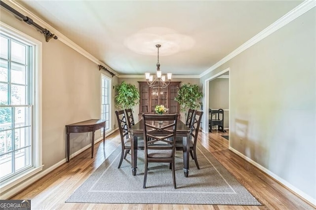 dining space with a healthy amount of sunlight, wood finished floors, and a notable chandelier