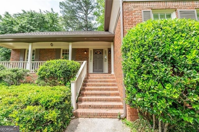 property entrance featuring brick siding and covered porch