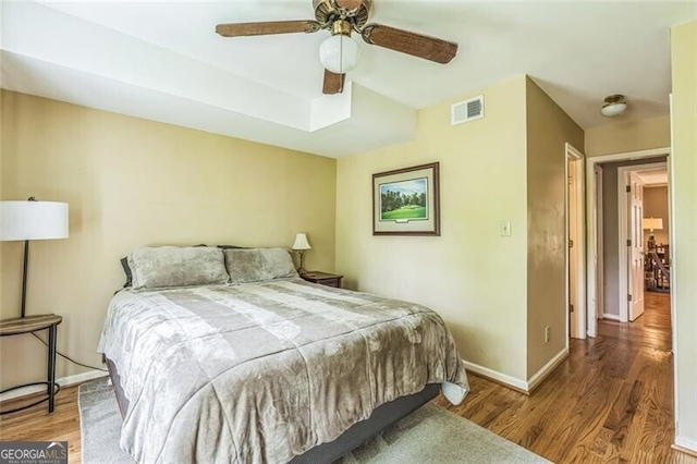 bedroom featuring visible vents, a ceiling fan, baseboards, and wood finished floors