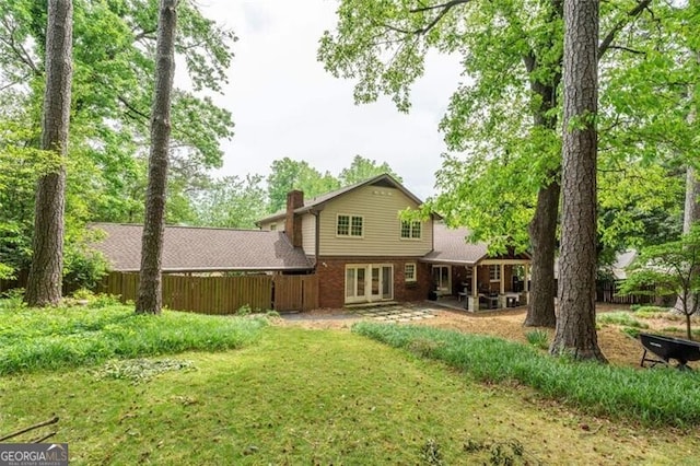 rear view of property with brick siding, fence, french doors, and a chimney