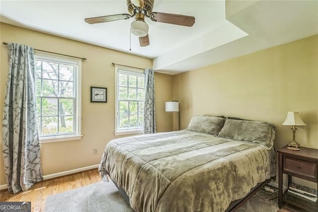 bedroom featuring a ceiling fan, baseboards, and wood finished floors