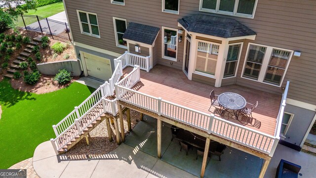 back of house with a wooden deck, a yard, an attached garage, a shingled roof, and stairs
