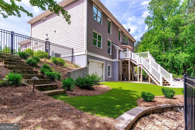 rear view of property with fence, stairs, a garage, a deck, and a yard