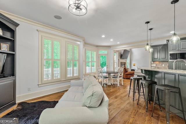 living area featuring crown molding, visible vents, wood finished floors, baseboards, and recessed lighting