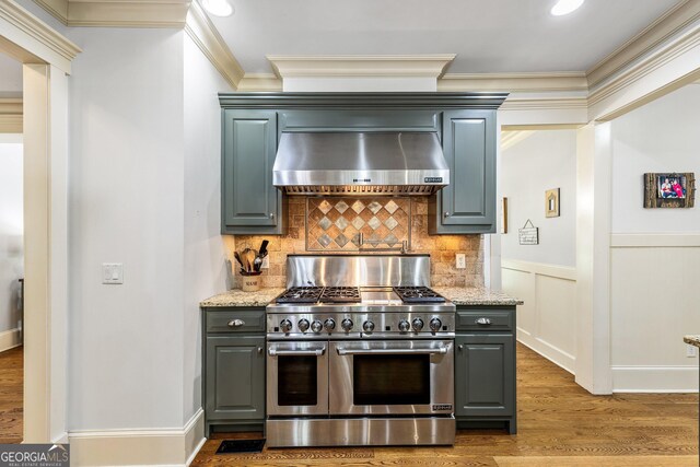 kitchen with ornamental molding, wood finished floors, gray cabinets, wall chimney exhaust hood, and double oven range