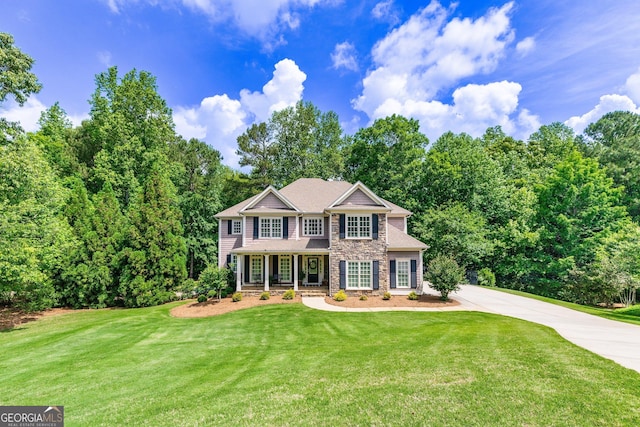 colonial-style house with a porch, a front lawn, driveway, and stone siding