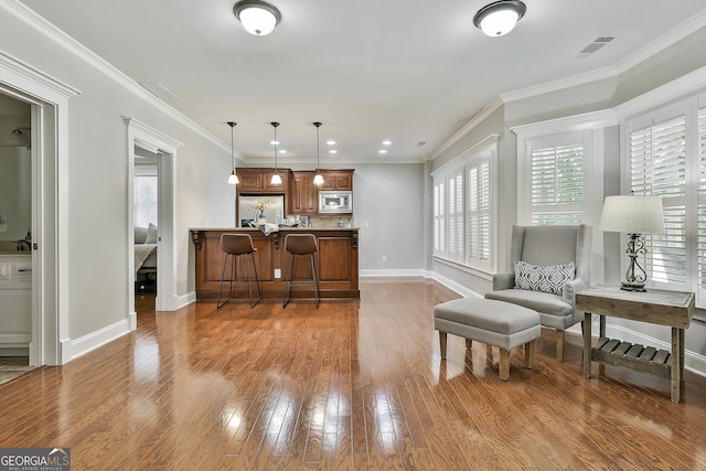 255 Ashmere Ct, Tyrone, GA 30290 - kitchen featuring appliances with stainless steel finishes, baseboards, brown cabinetry, wood finished floors, and ornamental molding
