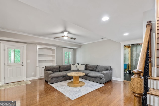 living room with crown molding, baseboards, and wood finished floors