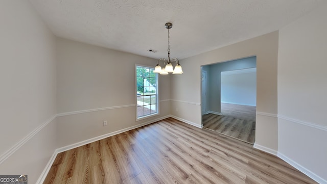 1229 Huntington Place Cir, Lithonia, GA 30058 - unfurnished dining area with a notable chandelier, a textured ceiling, baseboards, wood finished floors, and visible vents