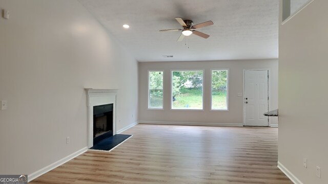 1229 Huntington Place Cir, Lithonia, GA 30058 - unfurnished living room featuring baseboards, a fireplace with raised hearth, a ceiling fan, and wood finished floors