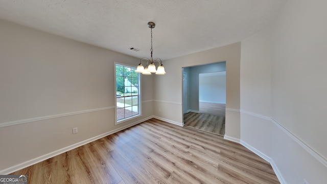 1229 Huntington Place Cir, Lithonia, GA 30058 - unfurnished dining area featuring a textured ceiling, visible vents, light wood-type flooring, baseboards, and an inviting chandelier
