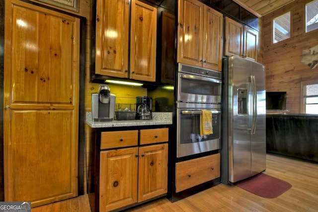 143 Katydid Rd, Morganton, GA 30560 - kitchen featuring light wood finished floors, appliances with stainless steel finishes, brown cabinets, and wooden walls