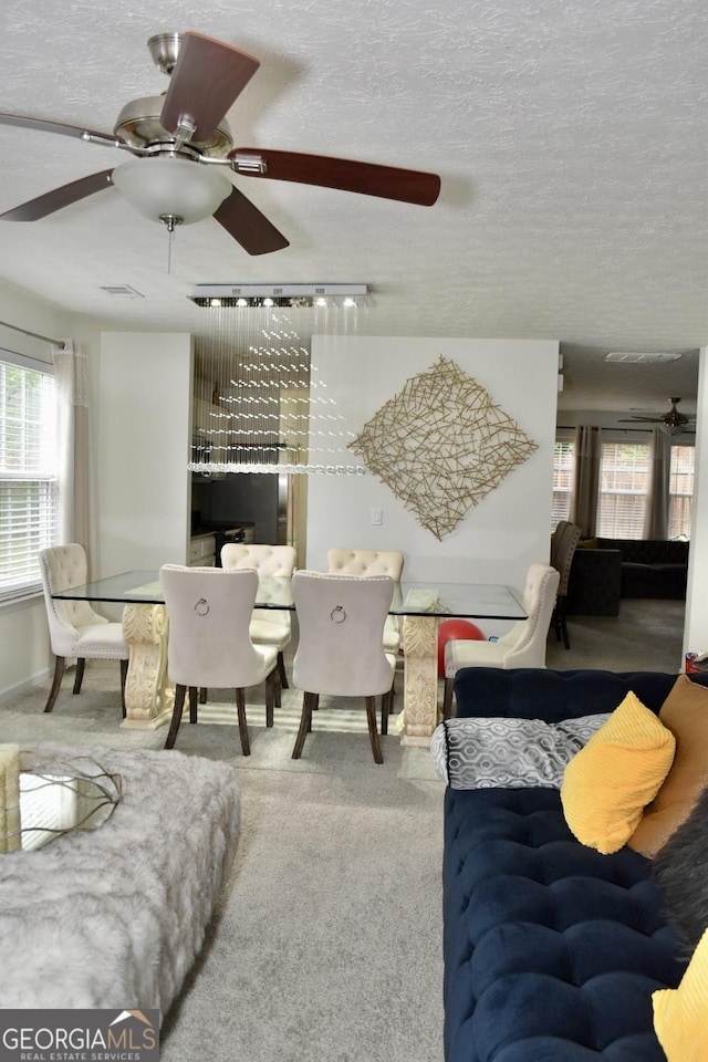 carpeted living room with a ceiling fan, a textured ceiling, and visible vents