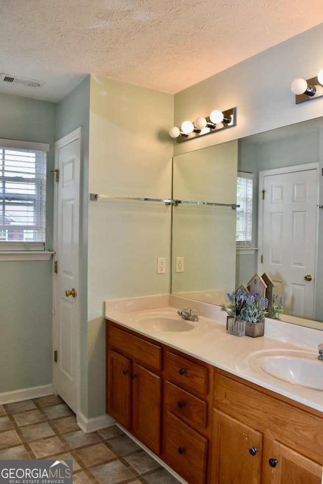 bathroom featuring visible vents, a sink, baseboards, and double vanity