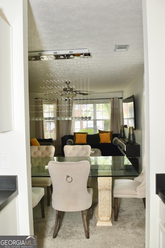 carpeted dining room with visible vents and a textured ceiling