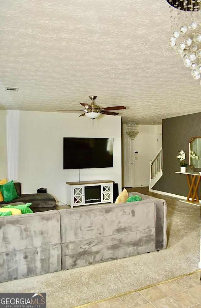 living area with stairs, a ceiling fan, and a textured ceiling