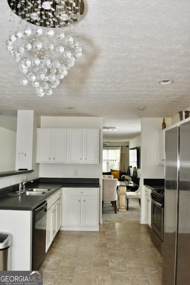 kitchen featuring dark countertops, a sink, stainless steel appliances, white cabinetry, and light tile patterned floors