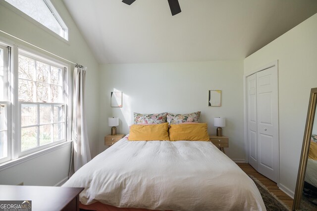 bedroom with a closet, ceiling fan, wood finished floors, and vaulted ceiling
