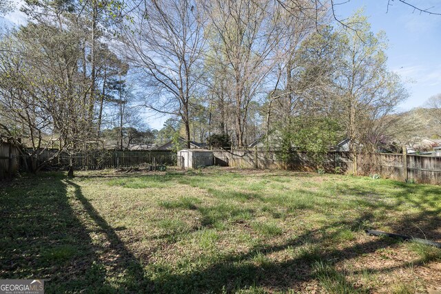 view of yard featuring an outdoor structure, a fenced backyard, and a shed