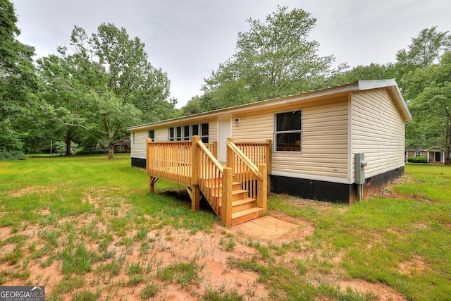 rear view of property with a yard, a deck, and crawl space