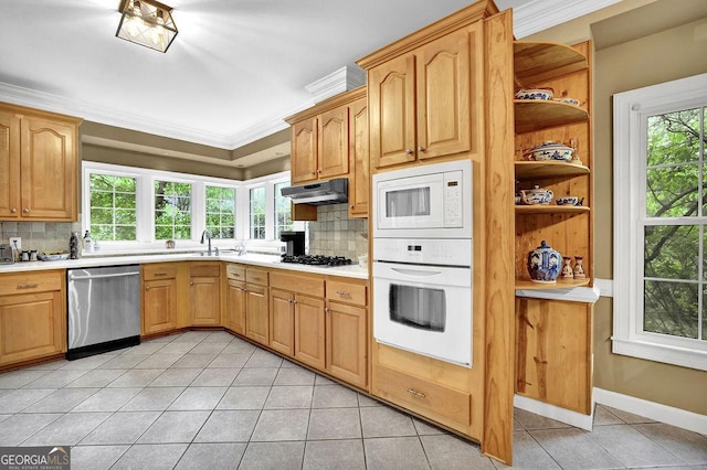 kitchen with white appliances, light tile patterned flooring, under cabinet range hood, decorative backsplash, and crown molding