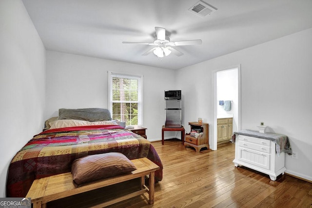bedroom featuring light wood finished floors, a ceiling fan, ensuite bathroom, and baseboards