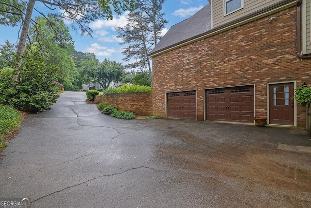 view of home's exterior featuring an attached garage, brick siding, and driveway