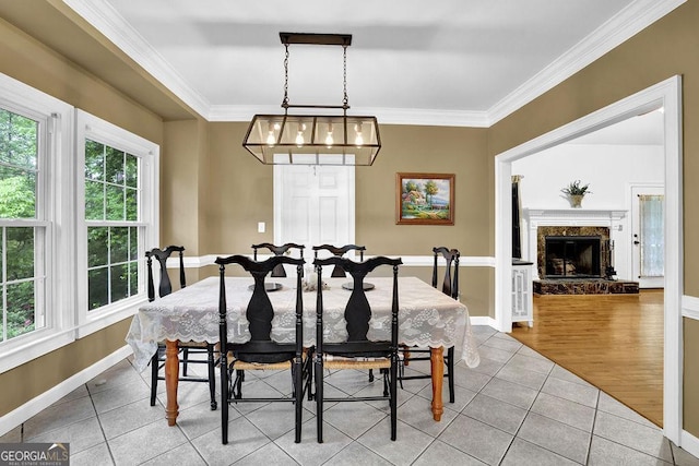 dining area with tile patterned floors, ornamental molding, baseboards, and a fireplace with raised hearth