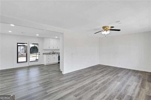 unfurnished living room featuring dark wood-style flooring, a ceiling fan, baseboards, and recessed lighting
