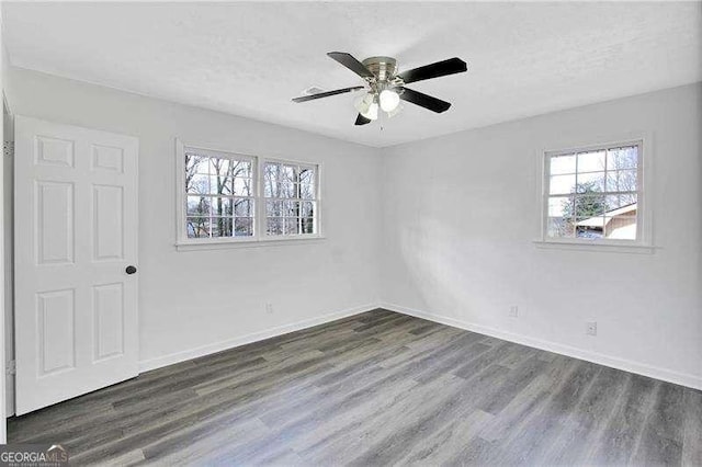 unfurnished room featuring plenty of natural light, wood finished floors, baseboards, and a textured ceiling