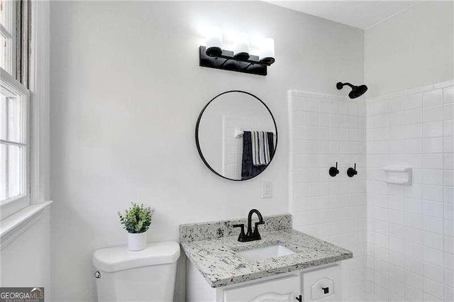 full bathroom with a tile shower, toilet, and vanity