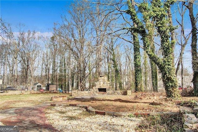 view of yard featuring an outdoor stone fireplace and fence
