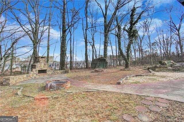 view of yard featuring an outdoor stone fireplace and a patio